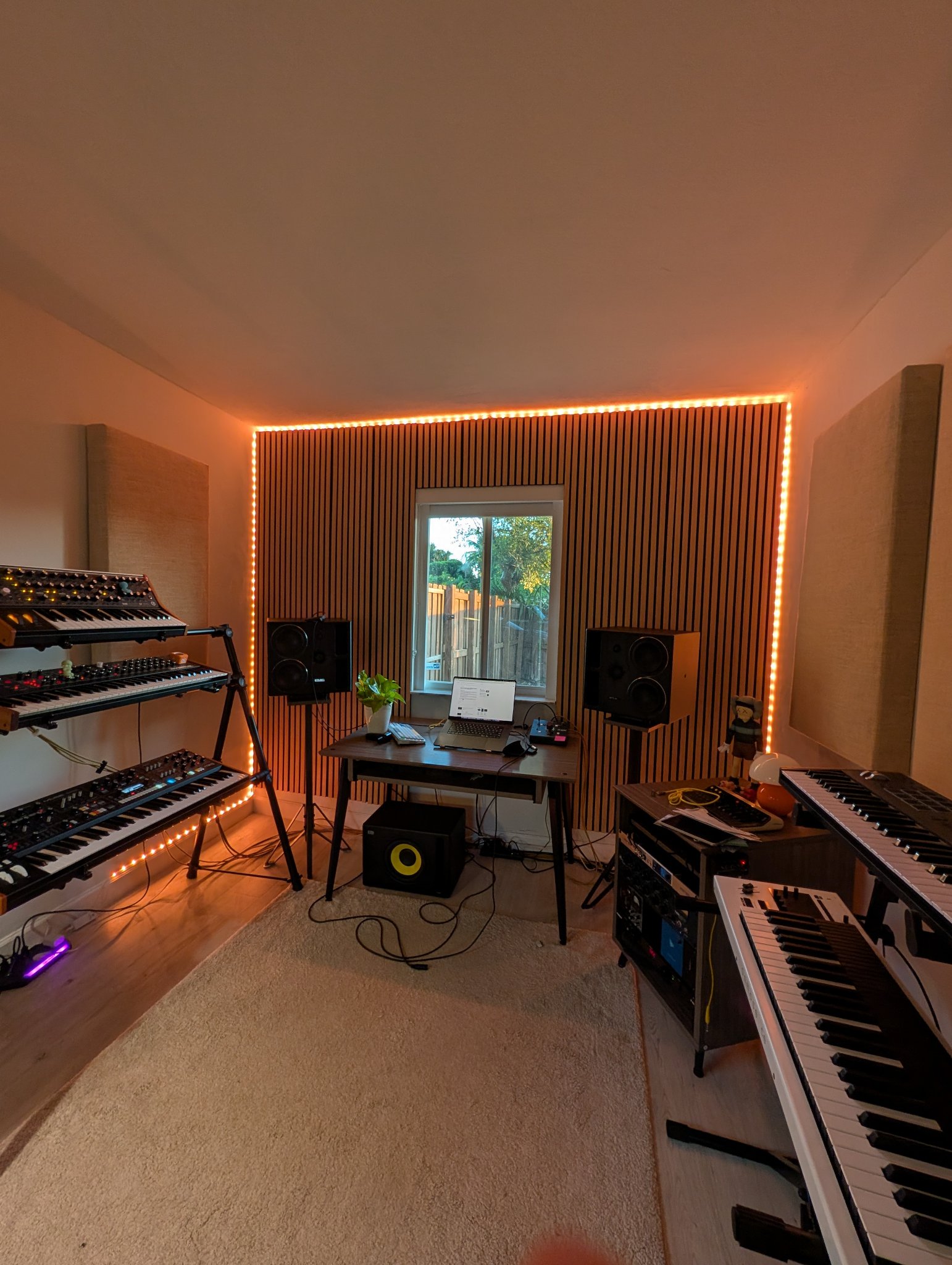 Wood slat accent wall with music-reactive LED lighting in a home studio