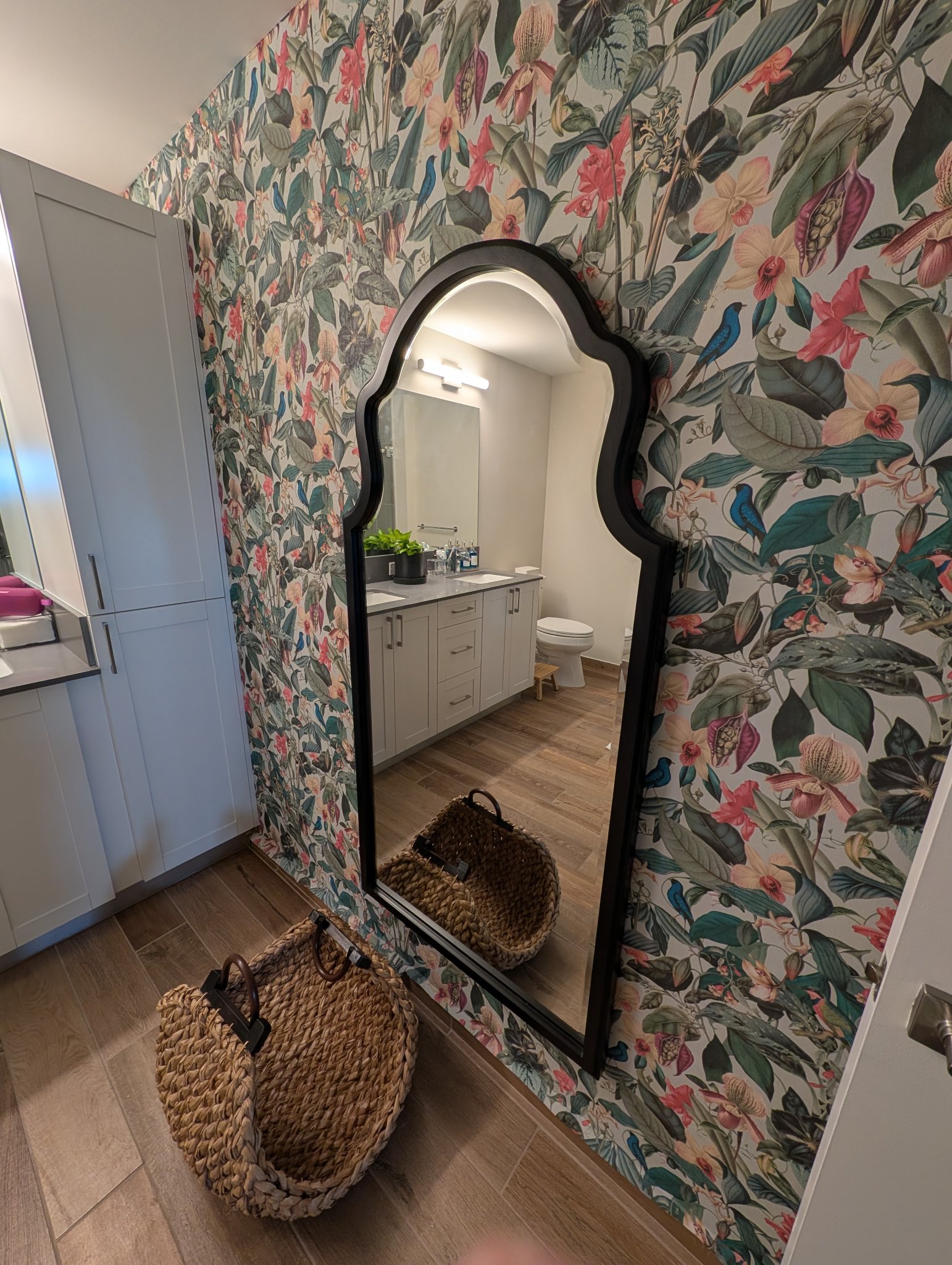 Decorative mirror mounted on a floral wallpaper accent wall